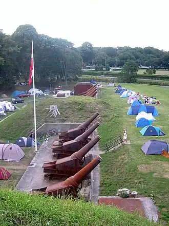 Zicht over het fortterrein met houwitsers en kampeerders