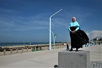 De Scheveningse vissersvrouw Gieltje den Heijer op de nieuwe sokkel van het monument van de Vissersvrouw voor het monument van de Vissersvrouw