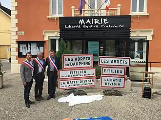 De burgemeesters van drie voormalige gemeenten voor het gemeentehuis te Les Abrets met de oude en de nieuwe plaatsnaamborden