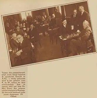 Foto van de competitiewedstrijd tussen Schaakclub Utrecht en de Amsterdamsche Schaakclub, januari 1931. Rechts aan het eerste bord Max Euwe tegen Adolf Olland. Het A.S.C. won deze wedstrijd met 3½-6½[1]