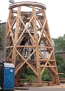 Gedeeltelijk gerestaureerde houten achtkant met boventafelement, veldkruisen en enkele veldregels