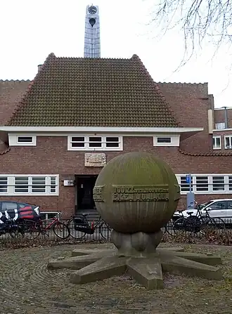 Het monument met op de achtergrond een gevelsteen van Trapman (maart 2013)