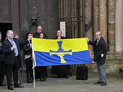 Het uitrollen van de provincievlag in de kathedraal van Durham in november 2013. James Moffat, de ontwerper van de vlag, is rechts te zien terwijl hij de vlag vasthoudt