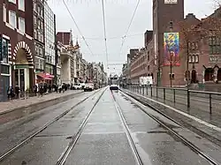 Damrak met entree van de Beurspassage links, Centraal Station aan het einde en het Beursplein rechts, 2024