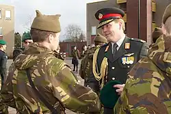 Kroonprins Willem-Alexander reikt na het volbrengen van de commando-opleiding de groene baret uit aan een nieuwe commando die een mutsdas draagt (dec 2009)