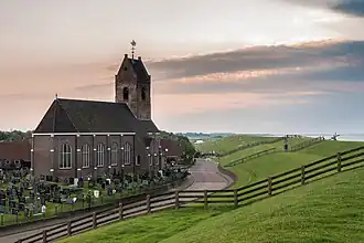 Mariakerk van Wierum met rechts de zeedijk en de Waddenzee (2013)