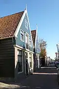 Houten huis met houten topgevel boven een bakstenen pui