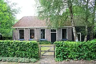 Daglonershuisje met houten staldeel onder pannengedekt schilddak