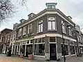 Winkelwoonhuis, in de late 19de eeuw gebouwd in een sobere eclectisch- classicistische bouwtrant, pui op de hoek uit 1924.