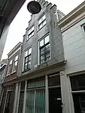 Winkelwoonhuis uit de 16de eeuw, mogelijk uit 1563, in renaissancevormen, gemoderniseerd en van een winkelpui voorzien in de 19de eeuw. Bijzondere hoofdstructuur met een kap met dwarskappen.