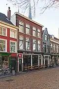 Dubbel bedrijfspand met bovenwoningen, rond1905 gebouwd in een sobere eclectische bouwtrant met bescheiden kenmerken van de Nieuwe Kunst.