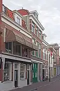 Bedrijfspand met bovenwoning, in 1900 gebouwd in een eclectische bouwtrant.