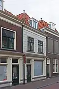 Winkelwoonhuis, 18de-eeuws of vroeg-19de-eeuws van karakter, met winkelpui uit het laatste kwart van de 19de eeuw in eclectisch-classicistische stijl.