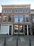 Blokje van twee panden met beneden- en bovenwoningen en een winkelruimte, rond 1900 gebouwd in een rijke eclectische bouwtrant met elementen uit classicisme en neorenaissance.