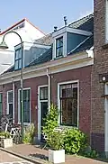 Woonhuis in rijtje van drie, in opzet identieke arbeiderswoningen uit het midden van de 19e eeuw, waarschijnlijk uit 1861, in sobere traditioneel-neoclassicistische vormen. Het pand is voor de gemeente Delft van belang vanwege de cultuurhistorische en architectuurhistorische waarde en van belang als onderdeel van het rijtje Doelenstraat 75-79.