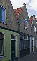 Woonhuis in traditionele vormen, mogelijk uit de late 18de of vroege 19de eeuw, opgenomen in een rijtje van vier vrijwel gelijkvormige, maar niet alle gelijktijdig gebouwde woningen.