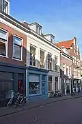 Breed winkelwoonhuis, in oorsprong dubbelpand, mogelijk uit de 17de eeuw, gemoderniseerd in de 19de eeuw en voorzien van een voorgevel in sobere eclectisch-classicistische vormen.