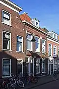 Pand met twee woningen onder één kap met de scheiding onder de nok. In het begin de 19de eeuw opgetrokken in sobere traditionele vormen.