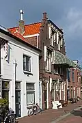 Pand met beneden- en bovenwoning, in 1906 gebouwd in een decoratieve bouwtrant met traditionalistische kenmerken en invloeden van de Nieuwe Kunst.