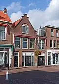 Winkelwoonhuis, in opzet mogelijk uit de 17e eeuw of ouder, met een, deels als topgevel beëindigde, voorgevel uit 1911 in neorenaissance vormen.