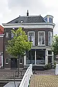 Winkelwoonhuis, in de tweede helft van de 19e eeuw in een traditionalistisch-classicistische bouwtrant ontworpen als hoekpand, wellicht tegelijk met het links belendende pakhuis Verwersdijk 118. Het is van belang vanwege de relatie met het links belendende pand en vanwege de bijzondere hoekoplossing. Een toegevoegde waarde wordt gevormd door de ligging op een straathoek waar de architectuur op inspeelt.