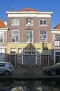 Winkelwoonhuis met voorgevel uit de tweede helft van de 19e eeuw in een eclectisch-classicistische stijl. Winkelpui in vrij strakke vormen, in 1932 ontworpen door J.B.A. Loomans en in 1934 in gewijzigde vorm uitgevoerd. Achter het hoofdhuis een iets smaller, in aanleg mogelijk ouder achterhuis. Het pand is voor de gemeente Delft van algemeen belang vanwege de cultuurhistorische waarde. Het pand is van belang als voorbeeld van een eclectisch-classicistische stijl.