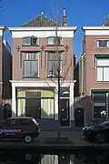 Winkelwoonhuis, in oorsprong 17e-eeuws of ouder, gewijzigd en van een nieuwe, traditionalistisch-classicistische voorgevel voorzien in de tweede helft van de 19e eeuw.