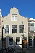 Pand met beneden- en bovenwoning, mogelijk uit de 19e eeuw. Voorgevel uitgevoerd als geblokt gepleisterde klokgevel.
