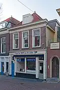 Winkelwoonhuis, in opzet uit de 17de eeuw, gemoderniseerd en van een lijst- gevel voorzien rond het begin van de 19de eeuw.