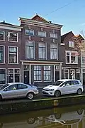 Winkelwoonhuis met voorgevel uit de 19de eeuw, maar in opzet ouder. Pui gewijzigd in 1911.