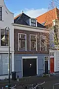 Bedrijfspand met bovenwoning, hoofdzakelijk uit de 19de eeuw, in traditioneel-classicistische vormen.