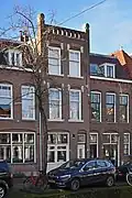 Bedrijfspand met bovenwoning in 1903 ontworpen door C.J.L. Kersbergen als onderdeel van een reeks van drie panden, Voorstraat 85 t/m 89a, met elk een eigen karakter in een bouwtrant met traditionalistische, Berlagiaanse kenmerken en Art Nouveau-invloeden.