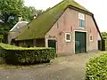 Boerderij waarvan het woonhuis dwars voor de stal is gebouwd en een pannen schilddak met hoekschoorstenen draagt
