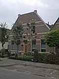 Linker van twee gespiegelde dubbele woonhuizen uit einde van de 19de of het begin van de 20ste eeuw.