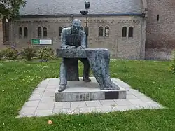 Beeld van Simon Vestdijk naast de kerk