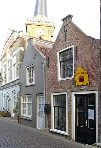 Pand met puntgevel, waarin een top-sieranker. In de gevel vlechtingen en een zoldervenster met negenruitsschuiframen