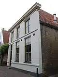 Huis met gepleisterde voorgevel en fraaie achtertopgevel boven een gepleisterde onderbouw
