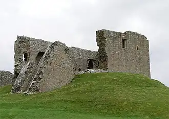 Duffus Castle vanaf de noordwestelijke zijde met de stenen toren op de motte op de voorgrond. Een deel van de toren is naar beneden geschoven.