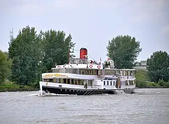 Salonstoomraderboot De Majesteit onderweg in de opvaart in de rivier de Noord.
