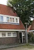 Blok met 2 keukenwoningen, zo genoemd vanwege destijds nieuwe plaatsing van keuken aan de voorzijde, aan de zijkant een houten topgevel, bouwstijl Amsterdamse School, aansluitend op andere keukenwoningen in Tuindorp Nieuwendam