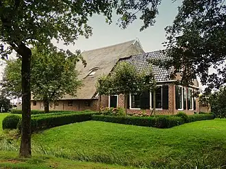 Kop-rompboerderij met zesruitsvensters, omgaande houten goot en schuur onder rieten dak