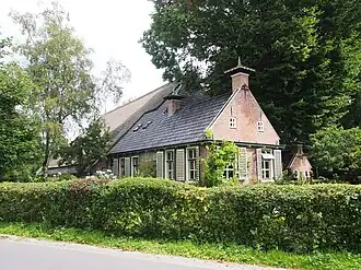 Kop-rompboerderij met woonhuis met topgevel en topschoorsteen met bord