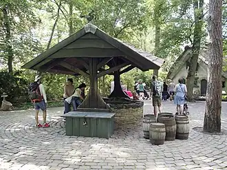 De waterput met op de achtergrond de woning.