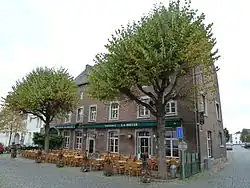 Groot huis van baksteen; segmentboogingang en segmentboogbenedenvensters in Naamse steen. Links van het huis een koetspoort