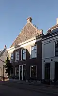 Huis met hoog schilddak. Lijstgevels. Begane grond met een verdieping. Schoorstenen op het schilddak