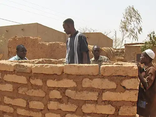 Bouw van een muur uit grote leemstenen in Burkina Faso