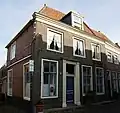 Pand met eenvoudige laat-18e-eeuwse gevel met rechte kroonlijst en dwarskap. Zijgevel aan de Dijkstraat en achterhuis
