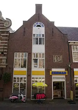 Uitgebouwde rechthoekige zaal met fors gedetailleerde gepleisterde achtergevel