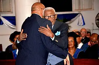 Dr. Eugène Gessel wordt gefeliciteerd door president Desi Bouterse bij de uitreiking van het eredoctoraat aan de Anton de Kom Universiteit van Suriname