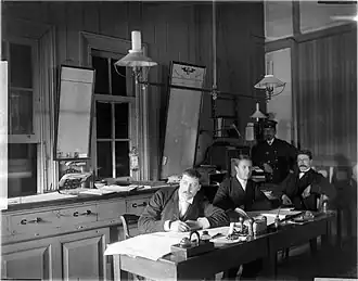 Kantoorpersoneel in het kantoor van de goederenloods van de Hollandsche IJzeren Spoorweg Maatschappij te Leiden; ca. 1885.